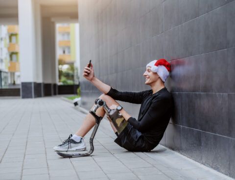 A man with a prosthetic running leg sitting down and taking a selfie