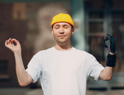 A man in white shirt and yellow hat holding camera.