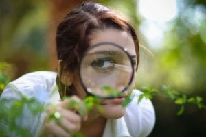 A person holds a magnifying glass to their eye