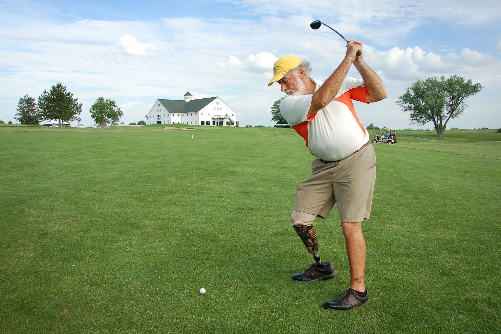 Amputee golfer swinging on the course.